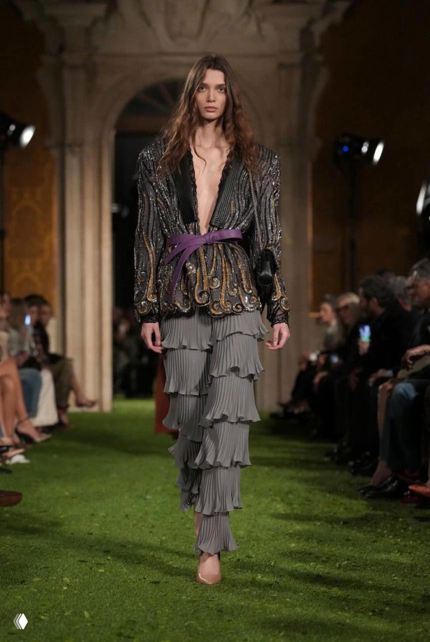 Женский образ: расшитый верх и многослойные плиссированные брюки идут по зелёному подиуму на показе Valentino в Риме.