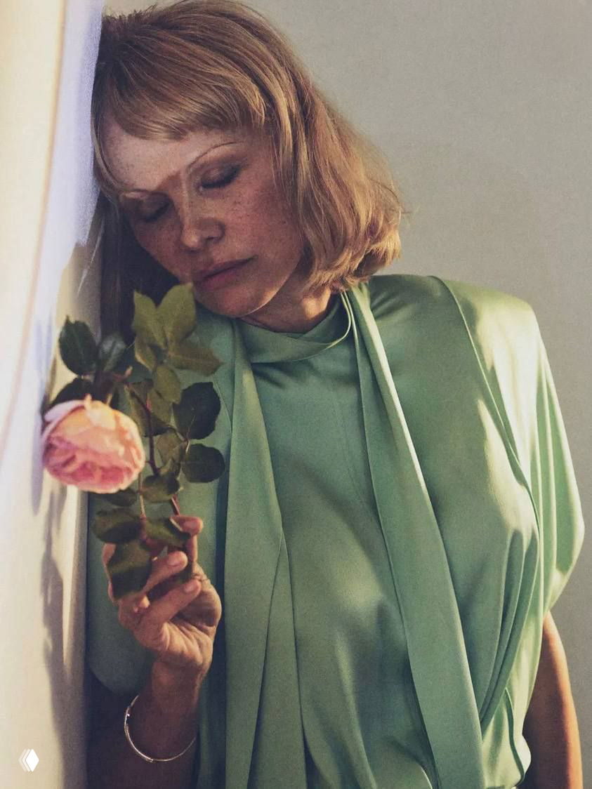 Крупный портрет Памелы Андерсон в зелёном платье с розой у лица, атмосферный кадр из фотосессии для глянца.