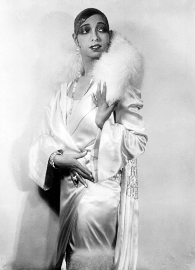 Чёрно‑белая студийная фотография начала XX века: женщина в атласном платье и накидке с пушистой меховой опушкой на плечах, ретро‑гламур.