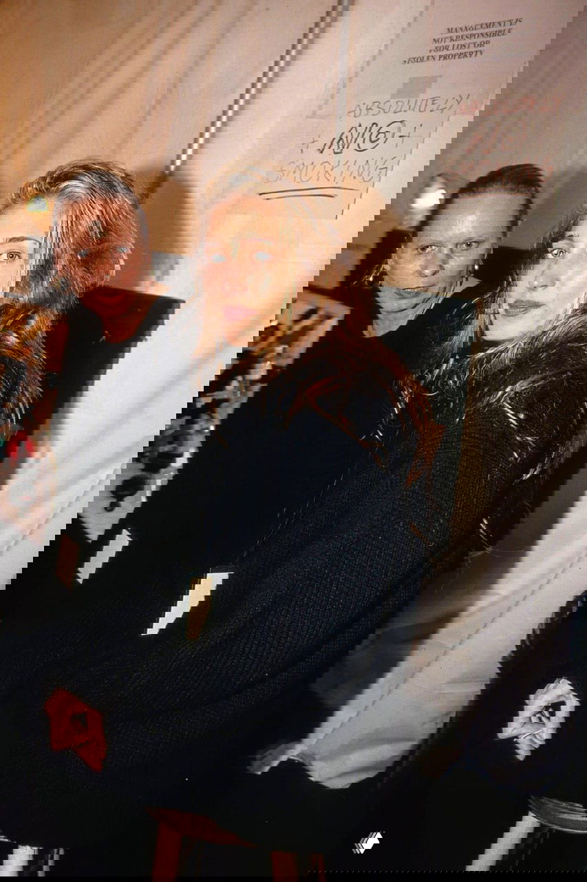 Бэкстейдж: две женщины в чёрной вязаной одежде у зеркала гримёрки, повседневная эстетика 90‑х и атмосфера подготовки к показу.