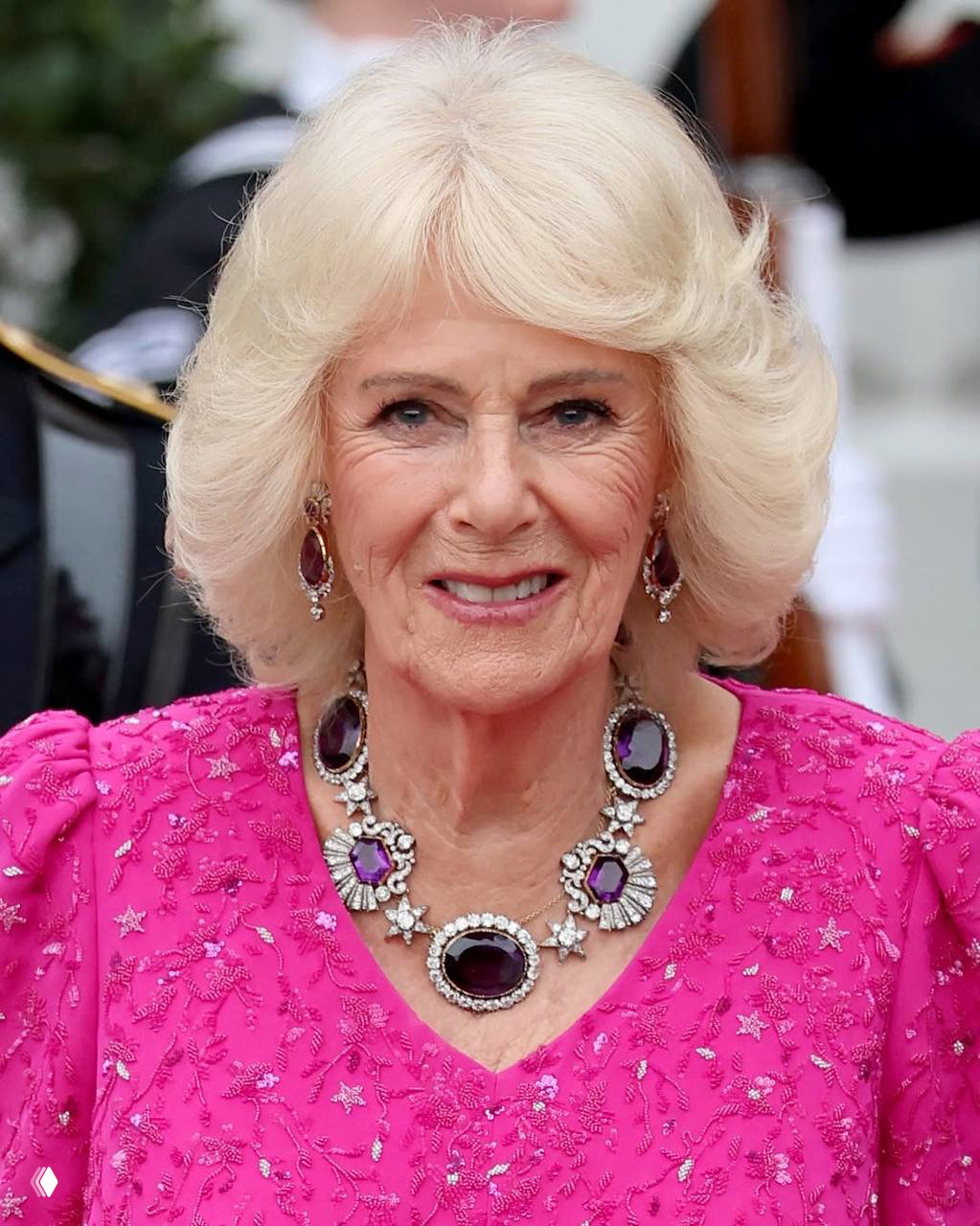 Крупный план улыбающейся женщины в ярком украшении и розовом платье — портретный кадр с церемонии на свежем воздухе.