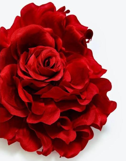 Крупный план искусственной розы ярко‑красного цвета с текстурированными лепестками — декоративный аксессуар, подходящий для подарка или украшения.