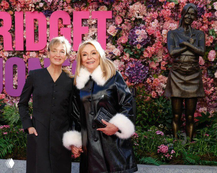 Рене Зеллвегер и писательница Хелен Филдинг позируют рядом со статуей Бриджит Джонс на фоне цветочной инсталляции во время церемонии.