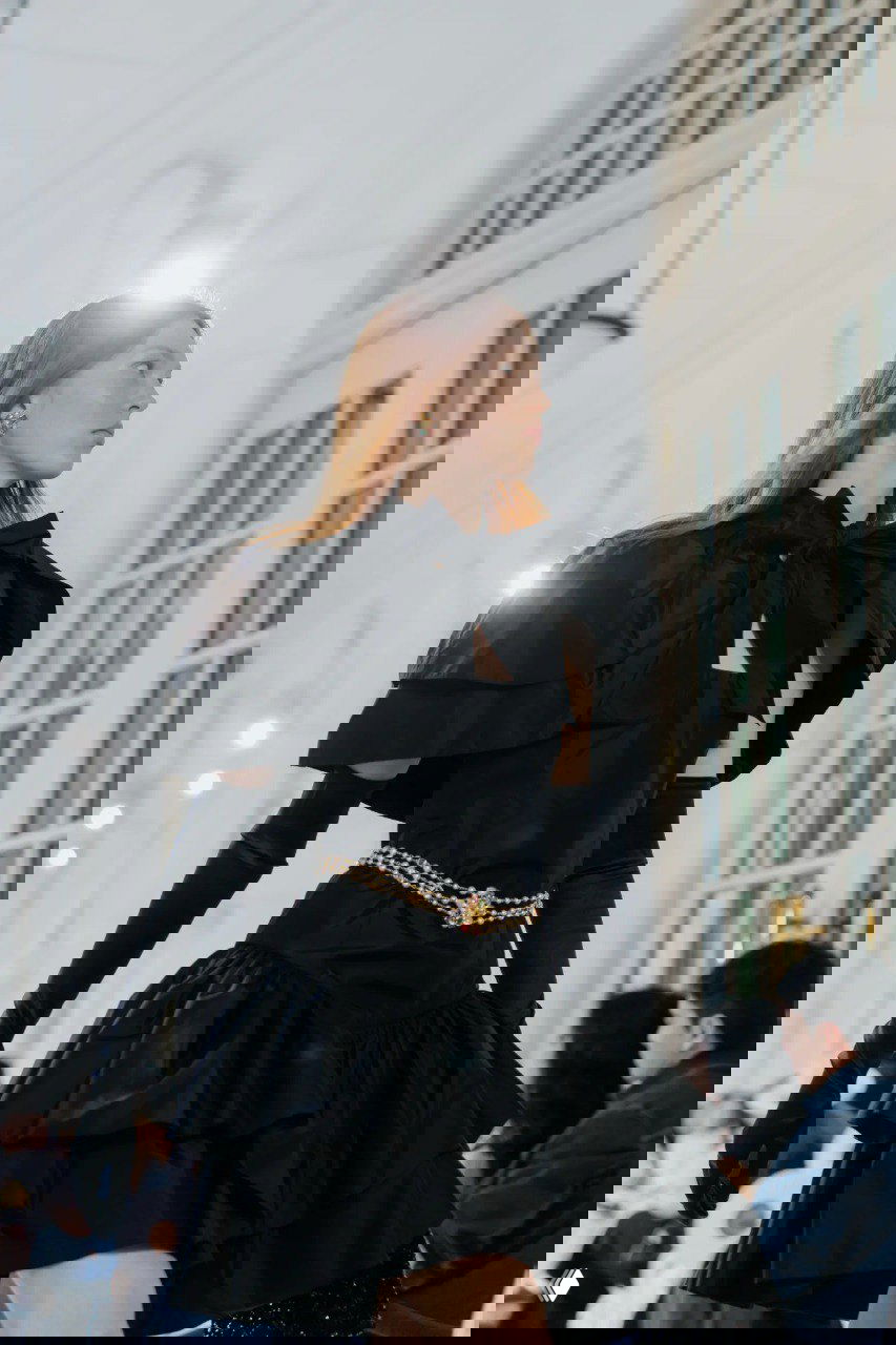 Чёрное многослойное платье с длинными перчатками и цепочными деталями — драматичный вечерний образ Chanel на мраморном подиуме показа в Сингапуре.