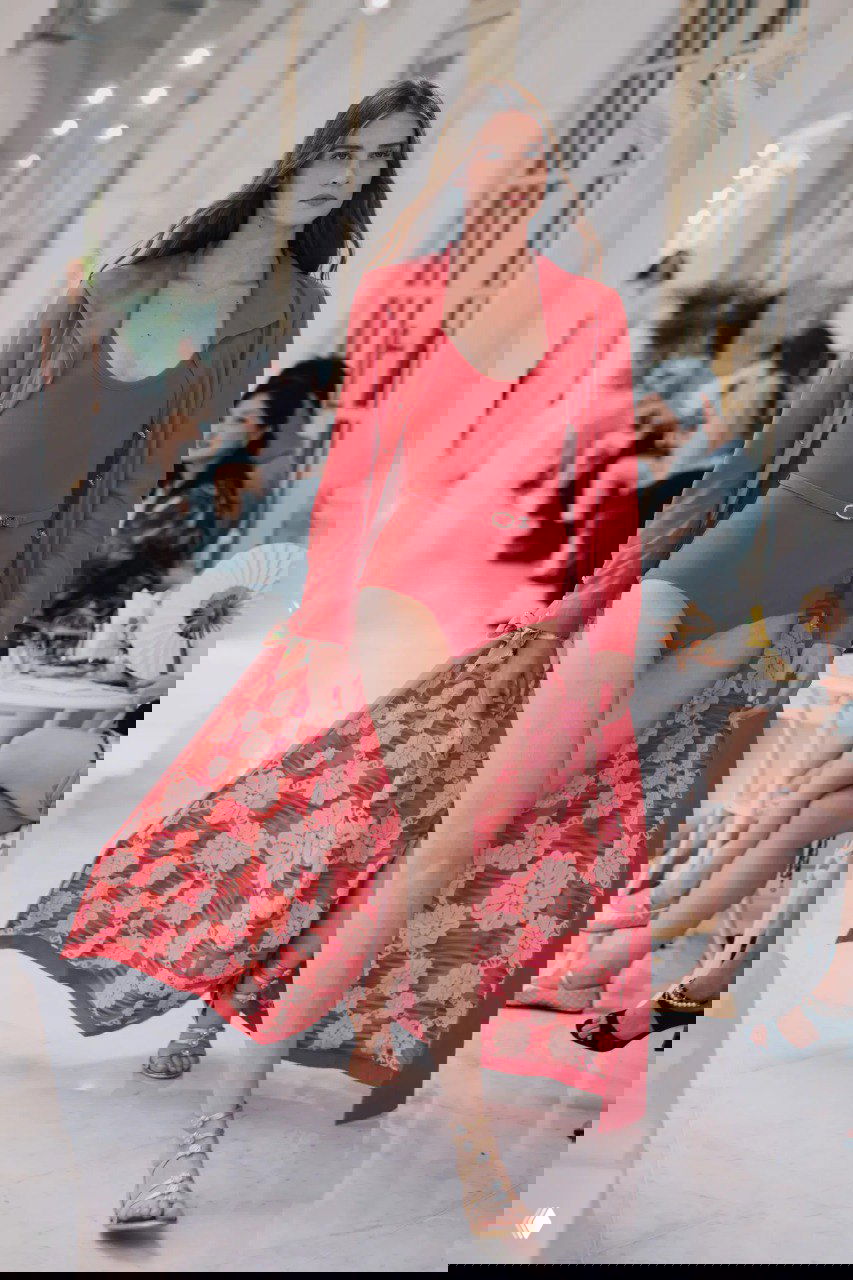 Яркий красный купальник с длинным декоративным плащом и узором в цветы — смелый летний образ из круизной коллекции Chanel на подиуме в Сингапуре.