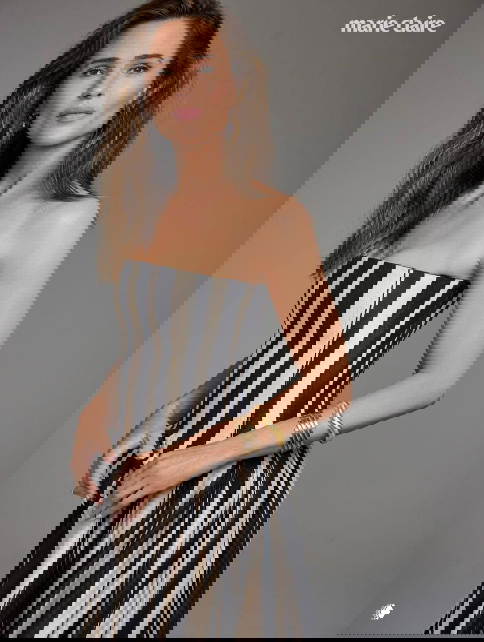 Портретная съемка женщины в полосатом корсете-платье, нейтральный серый фон, акцент на естественной внешности и украшениях.