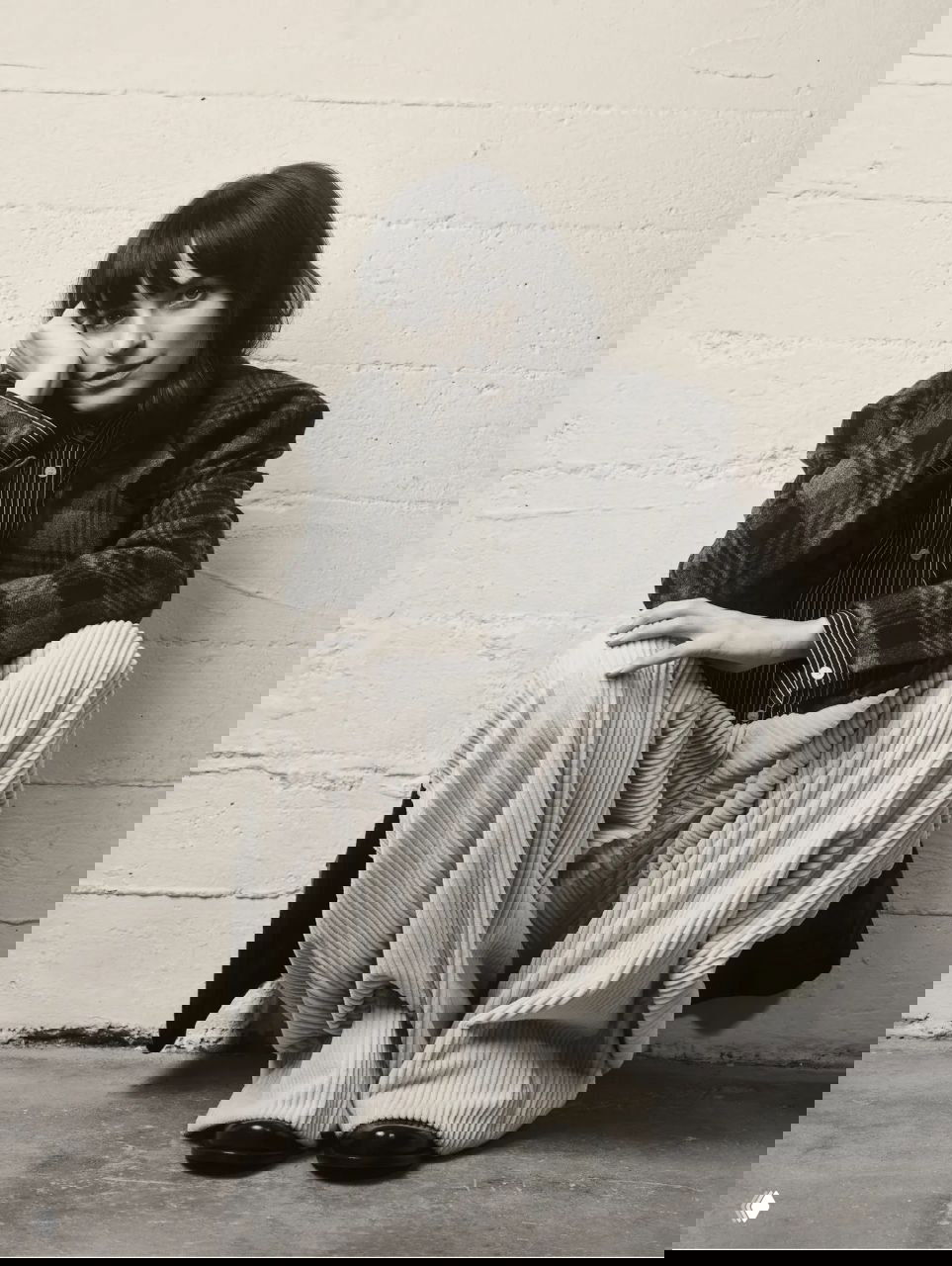 Чёрно‑белый портрет актрисы в клетчатом пиджаке и широких велюровых брюках; кадр создаёт интимную и задумчивую атмосферу съёмки.