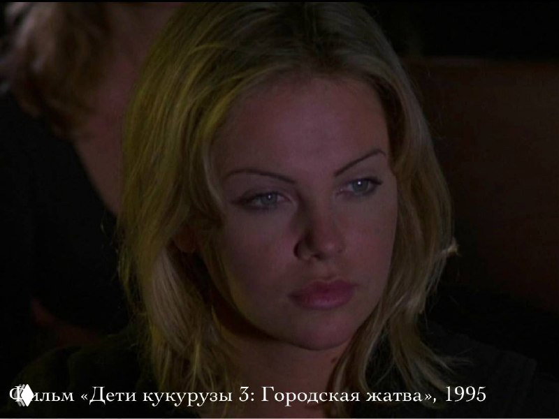 Кадр из фильма с молодой Шарлиз Терон (1995): крупный план лица в тёмной сцене, мягкое освещение и серьёзное выражение, ранняя роль в кино.