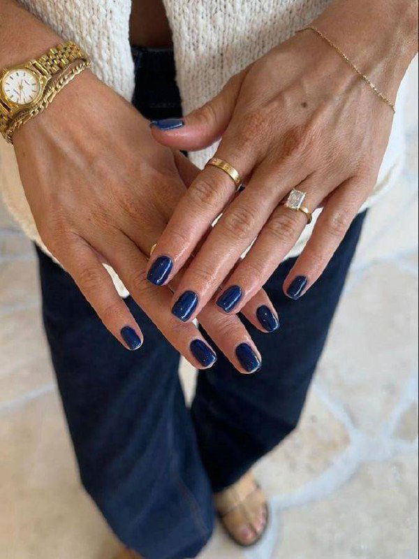 Руки с тёмно-синим металлическим маникюром на средней длины ногтях; видны золотые кольца и браслет, образ с денимом.