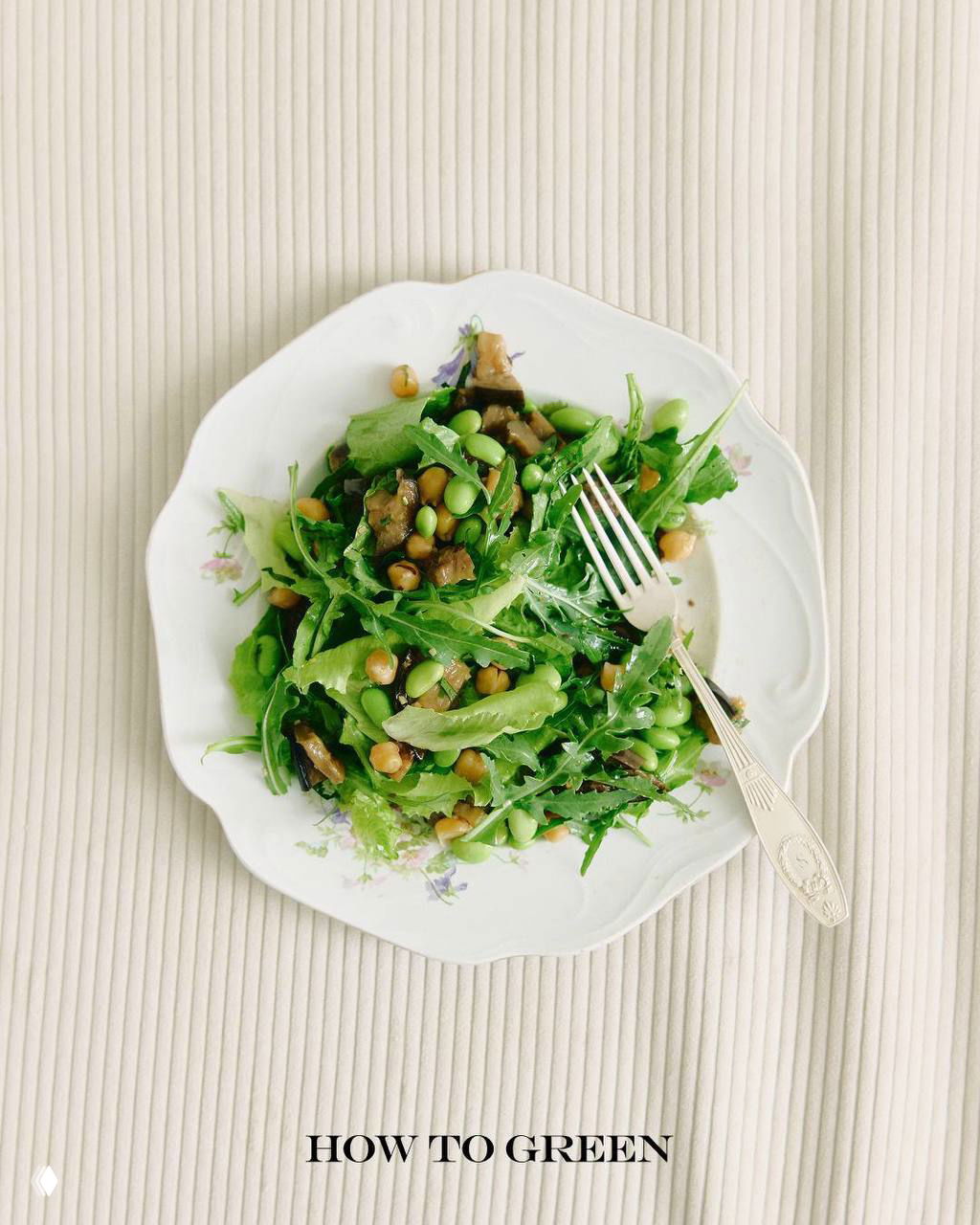 Плоская композиция с тарелкой зелёного салата, эдамаме и нутом на светлом фоне; фото ассоциируется с питанием и практиками wellness.
