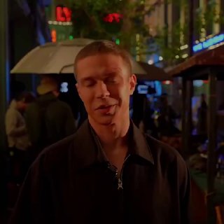 Глеб Калюжный на ночной улице Шанхая: портрет актёра в тёмной куртке на фоне неоновых огней, улиц и зонтов — атмосфера съёмок на локации.