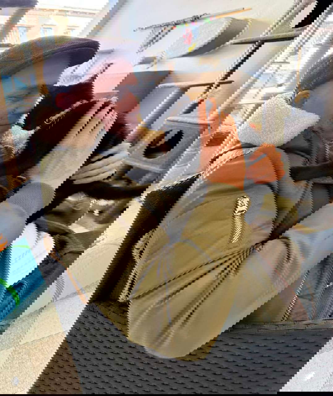 Актёр прижимает к себе чёрного кота в помещении приюта: кресло, когтеточки и окно на заднем плане создают тёплую сцену общения.