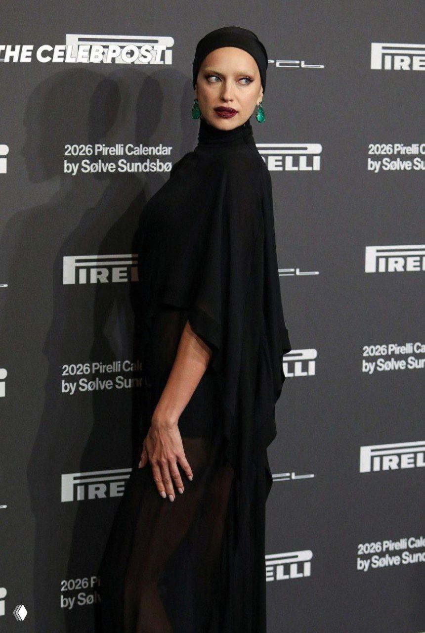 Трёхчетвертной снимок на красной дорожке Pirelli: чёрный наряд с полупрозрачной юбкой, подчёркнутый контур лица и осветлённые брови.