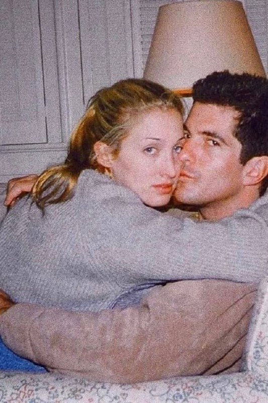 Пара на домашнем диване: женщина прижимается к мужчине, непринуждённый бытовой кадр в мягком свете, атмосферное архивное фото.