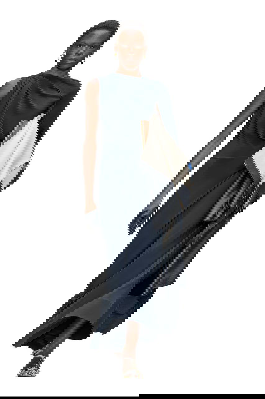 Модель в элегантном асимметричном темно-синем платье, в руках кожаная верхняя одежда — вечерне-офисная стилизация с драпировками и минимализмом.