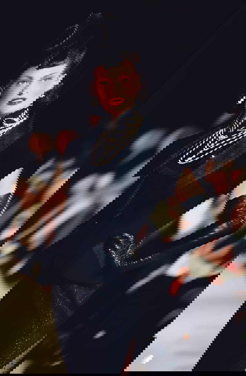 Модель в чёрном платье с длинными кожаными перчатками и многослойными украшениями на подиуме Dior осень‑зима 1997, драматичный силуэт и макияж.