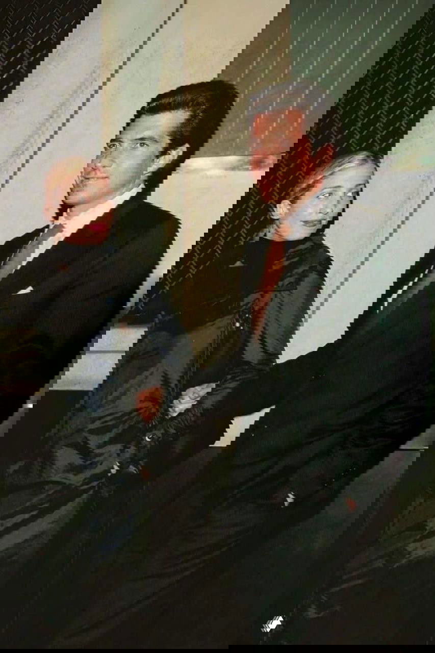 Момент свадьбы: женщина в белом платье с букетом и мужчина в тёмном костюме выходят вместе, торжественный кадр из семейного архива.