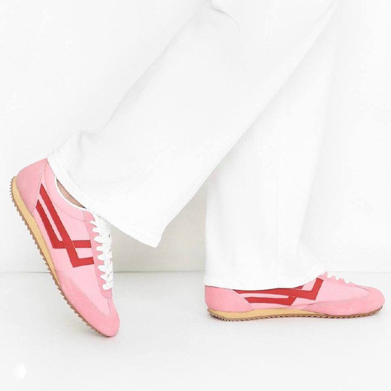 Розовые кроссовки Pro-keds на ноге в сочетании с белыми брюками, снимок в студии подчёркивает форму и цвет обуви.