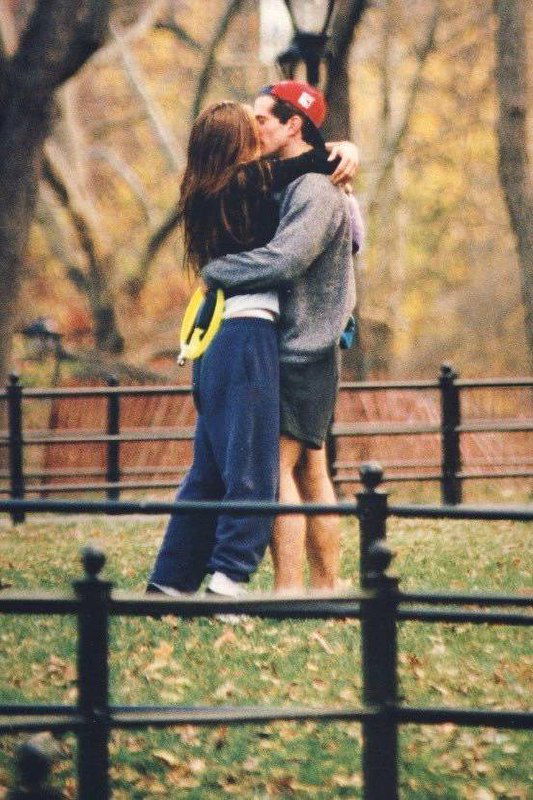 Пара в вечернем образе выходит из здания: мужчина в костюме, женщина в тёмной верхней одежде, кадр ночной прогулки в городе.