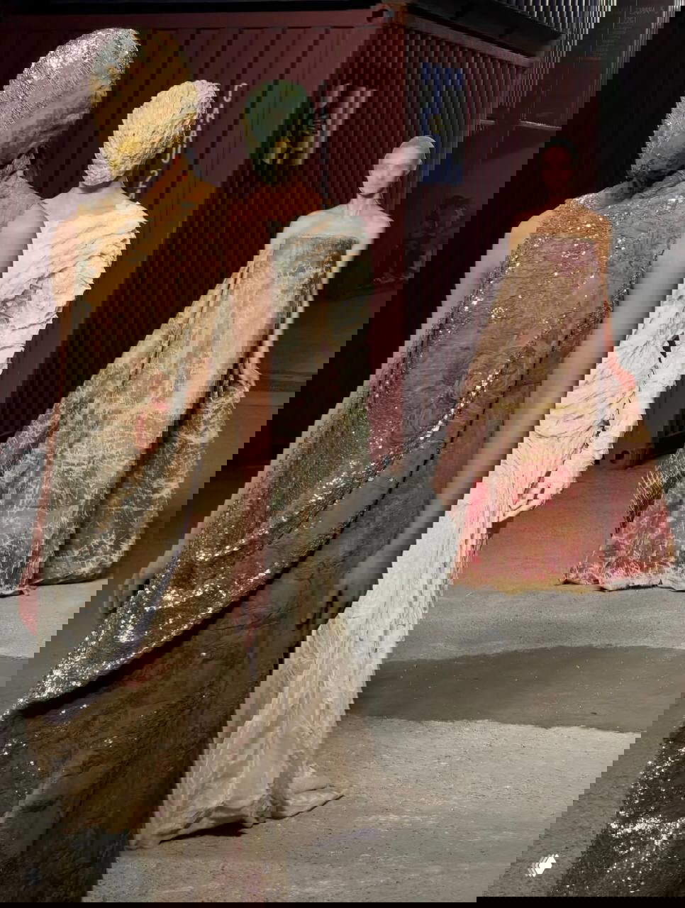 Группа моделей в длинных драпаных платьях и масках, несколько образов в кадре демонстрируют разнообразие техник Artisanal коллекции.