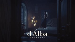 Тёмный атмосферный кадр кампейна d'Alba с логотипом бренда внизу кадра; художественная сценография и модель в глубине композиции.