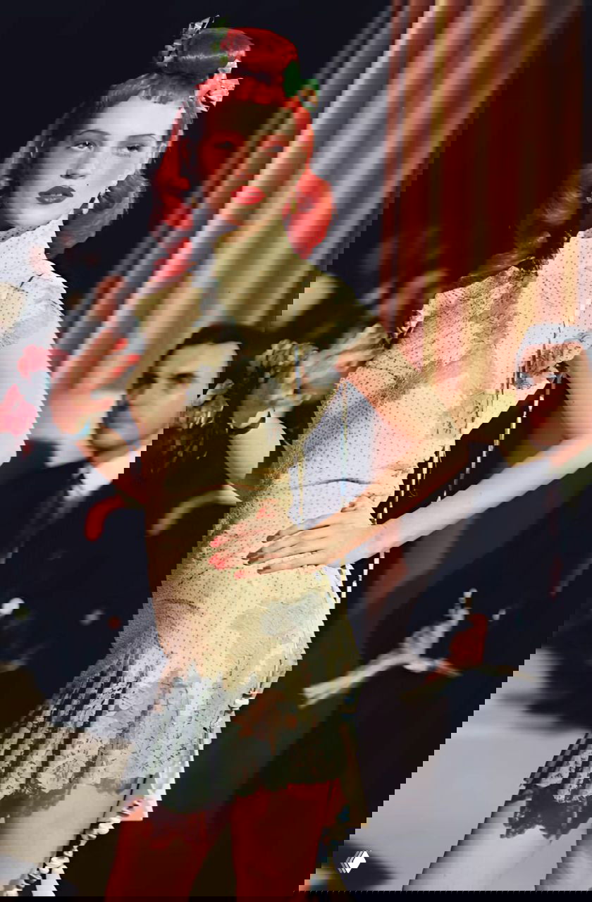 Модель в узком платье со светло‑голубыми вставками и лёгким воланом на показе Dior осень‑зима 1997, выразительный ретро‑макияж и зрители на заднем плане.