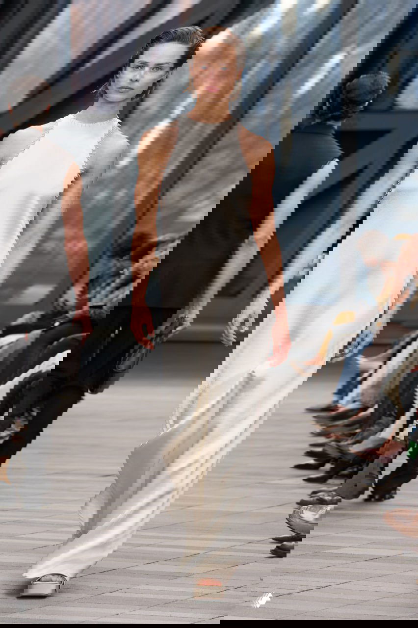 Лаконичное белое длинное платье на модели в показе Calvin Klein; простой силуэт и гладкая ткань подчёркивают минимализм коллекции Вероники Леони.