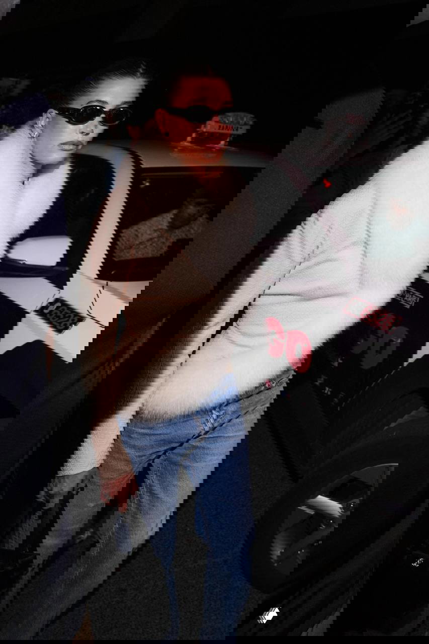 Женщина в длинном чёрном платье без бретелей позирует на фоне стилизованной сцены, образ для официального вечера и церемонии.