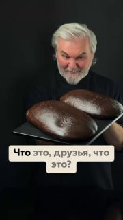Сергей Кириллов держит два тёмных ржаных панеттоне на подносе на тёмном фоне; на кадре видна подпись «Что это, друзья, что это?»