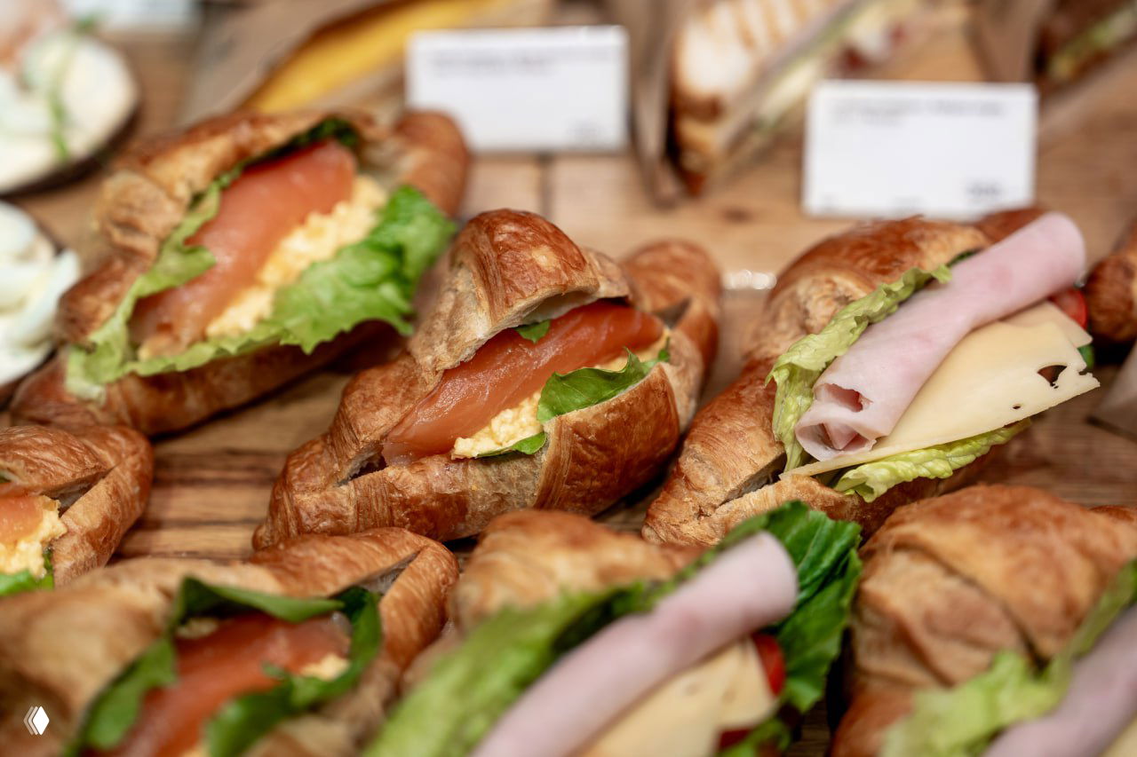 Круассаны с лососем, яйцом и ветчиной на витрине: пример готовых сэндвичей и изделий собственной кондитерской «Азбуки вкуса» для экспресс‑покупок и дегустаций