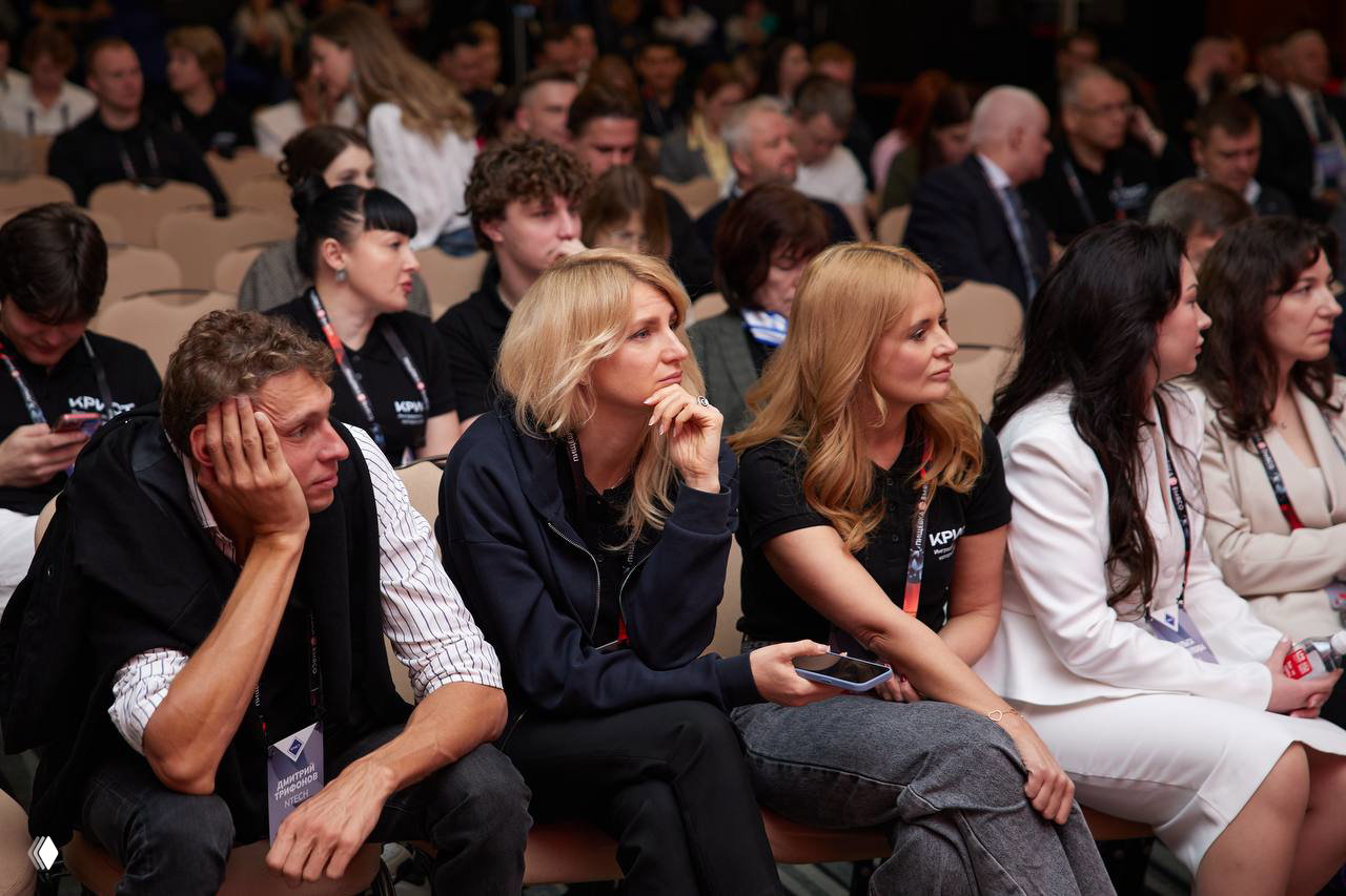 Слушатели в конференц-зале внимательно смотрят на сцену: ряды кресел заполнены, участники сосредоточены на докладах и обсуждениях.