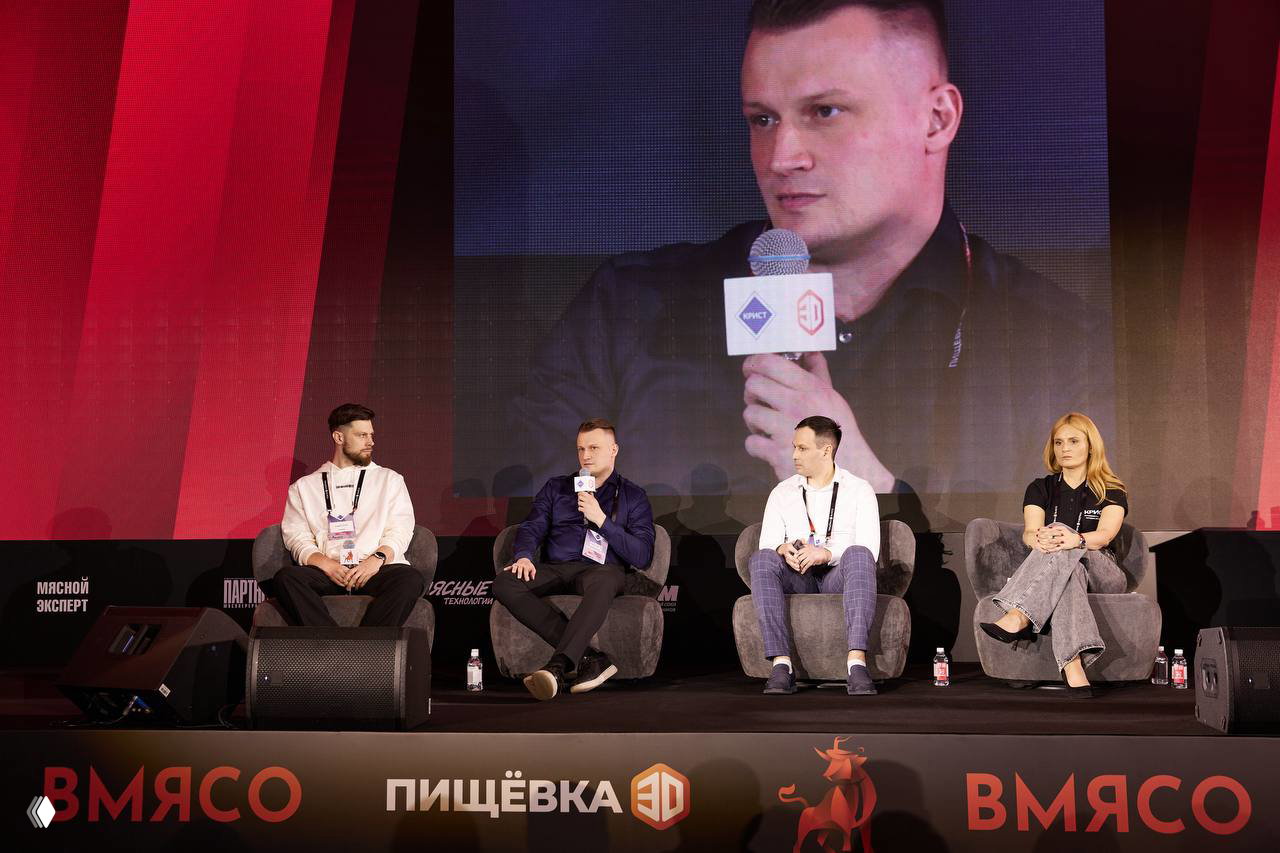 Панельная сессия на сцене ВМЯСО: модераторы и спикеры на креслах, крупный экран с проекцией и фирменные логотипы мероприятия.