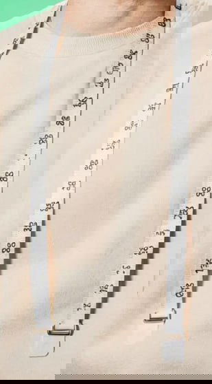 Крупный план свитера и декоративной ленты на модели из баннера; текстуры и артефакты намекают на нейросинтез изображения.