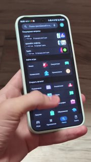 Крупный план руки, дотрагивающейся до экрана смартфона; видно меню приложений в тёмной теме — визуализация сценария сворачивания и вопроса UX.