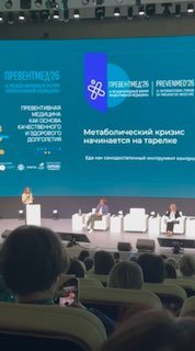 Сцена форума с крупным экраном и надписью «Метаболический кризис начинается на тарелке», панель спикеров и аудитория в зале мероприятия PreventMed.