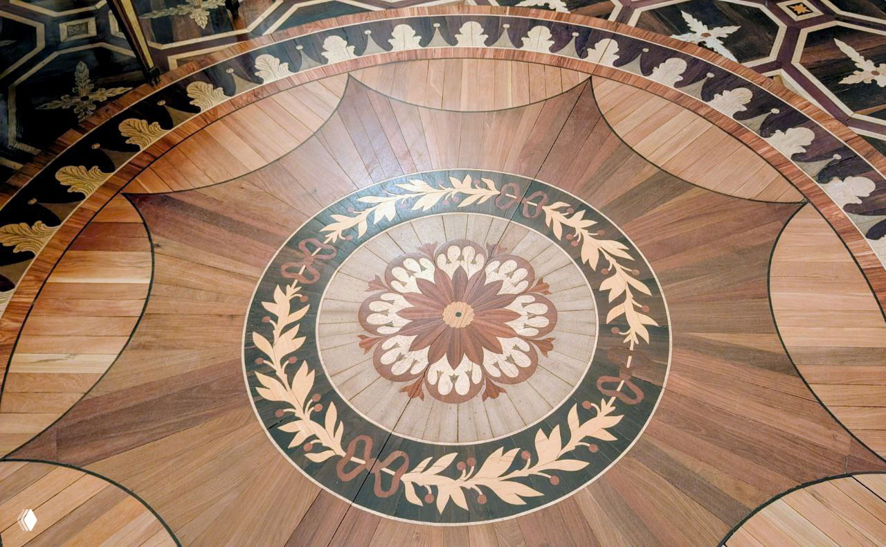 Фрагмент паркетного пола с декоративным круговым орнаментом, собранный из двенадцати редких пород дерева, виден идеальный художественный рисунок пола.