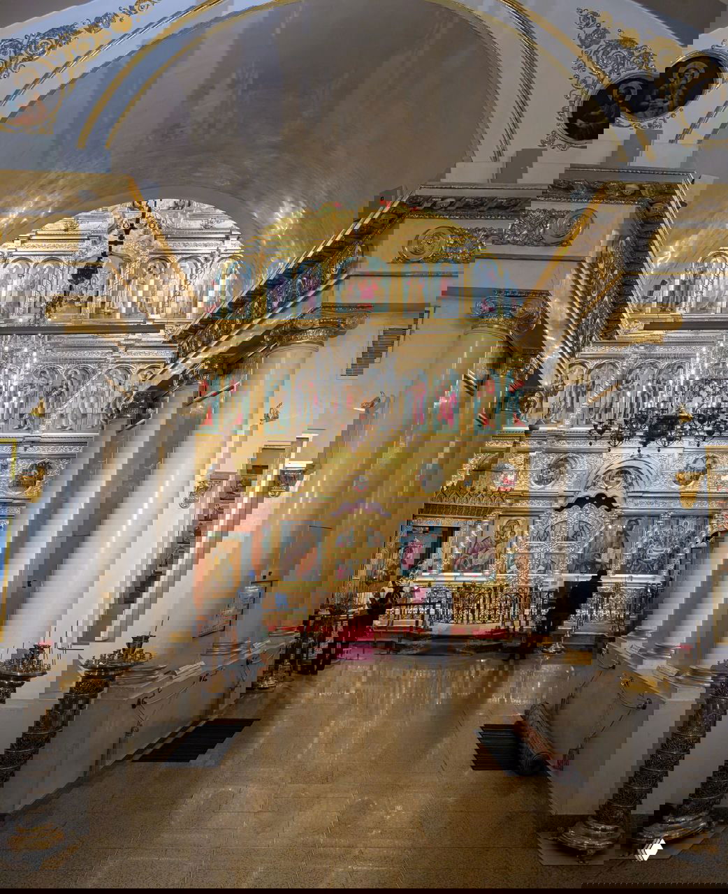 Вид интерьера храма: центральный неф и роскошный золоченый иконостас Третьяковской галереи, свечи и несколько посетителей в тихом молчаливом пространстве.