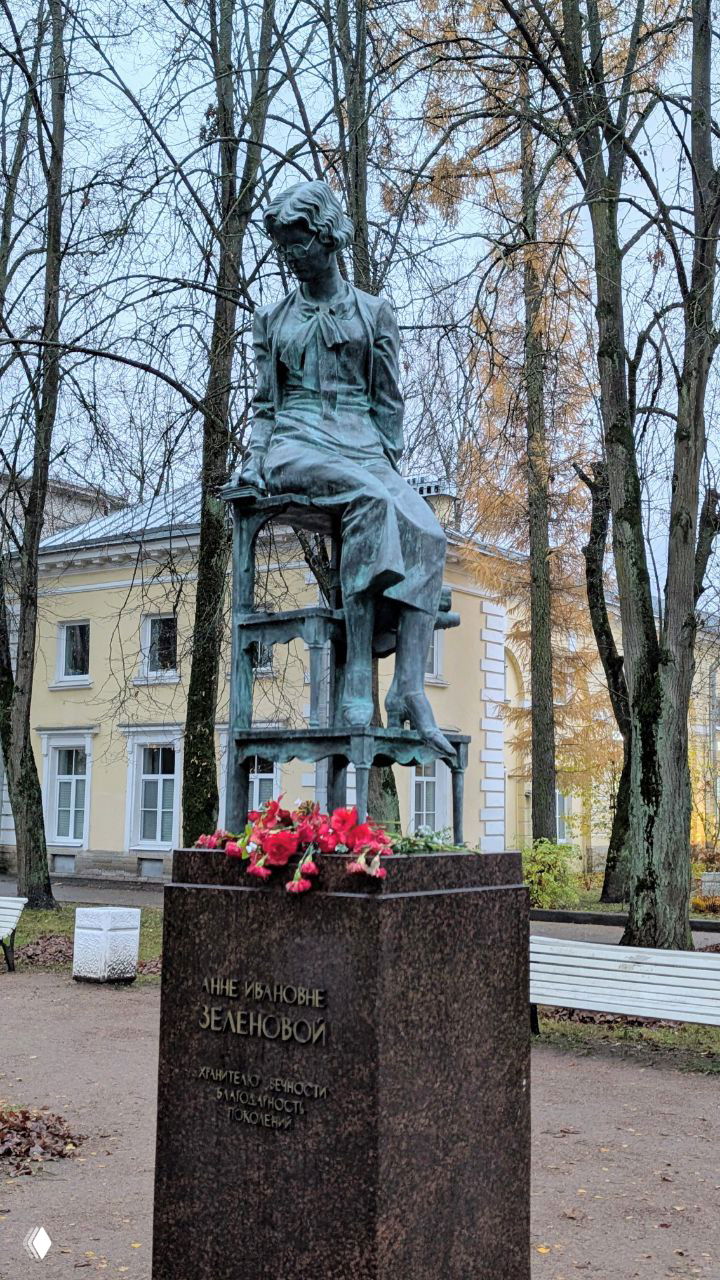 Памятник Анне Зеленовой на открытой площадке парка: бронзовая скульптура музейного сотрудника на постаменте среди деревьев и скамей.
