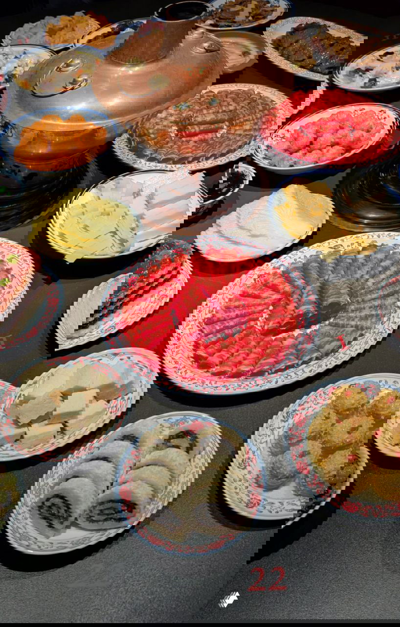 Стол, накрытый множеством традиционных китайских блюд и ингредиентов: тарелки с пластиночным мясом, роллами и сладкими рулетиками — новогодняя символика еды.