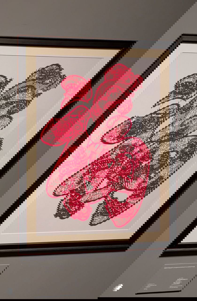 Тонкая бумажная вырезка в рамке — пример няньхуа или вырезной графики, красочный орнамент и традиционный символ удачи в рамке на стене музея.