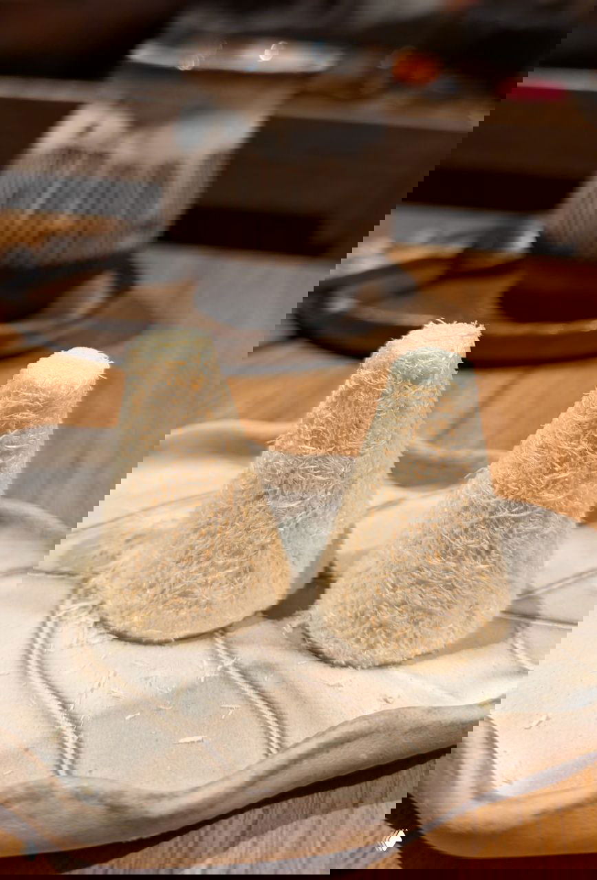 Две конусные сладкие пирамидки талкыш калеве на тарелке: тонкие сахарные нити свернуты в аккуратные рожки, поданы на керамике в ресторане.