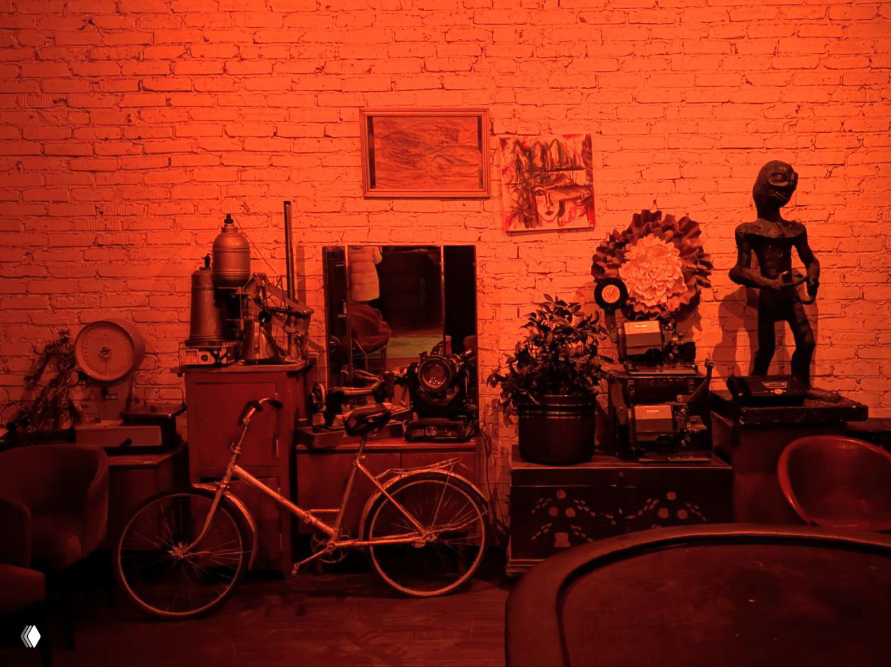 Интерьер с предметами и экспонатами в красном освещении: велосипеды, статуэтки и старые вещи в художественном лофте фабрики.