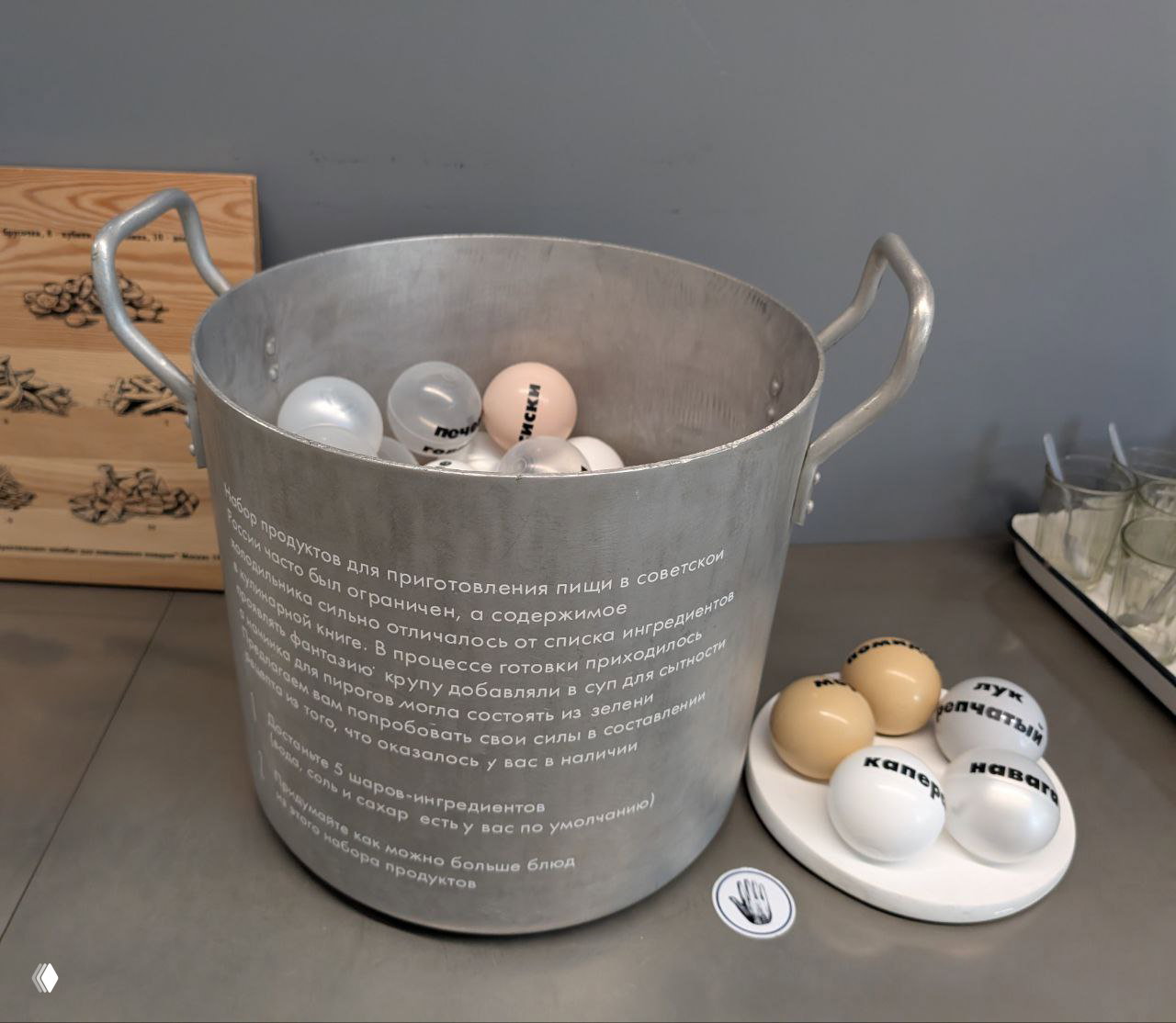 Крупный металлический котёл с шарами и подписью — инсталляция, иллюстрирующая ограниченный набор продуктов советской кухни.