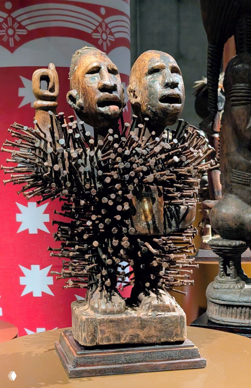 Нкиси нконди — ритуальная деревянная фигурка, утыканная гвоздями; крупный план показывает текстуру дерева и множество вбитых гвоздей.