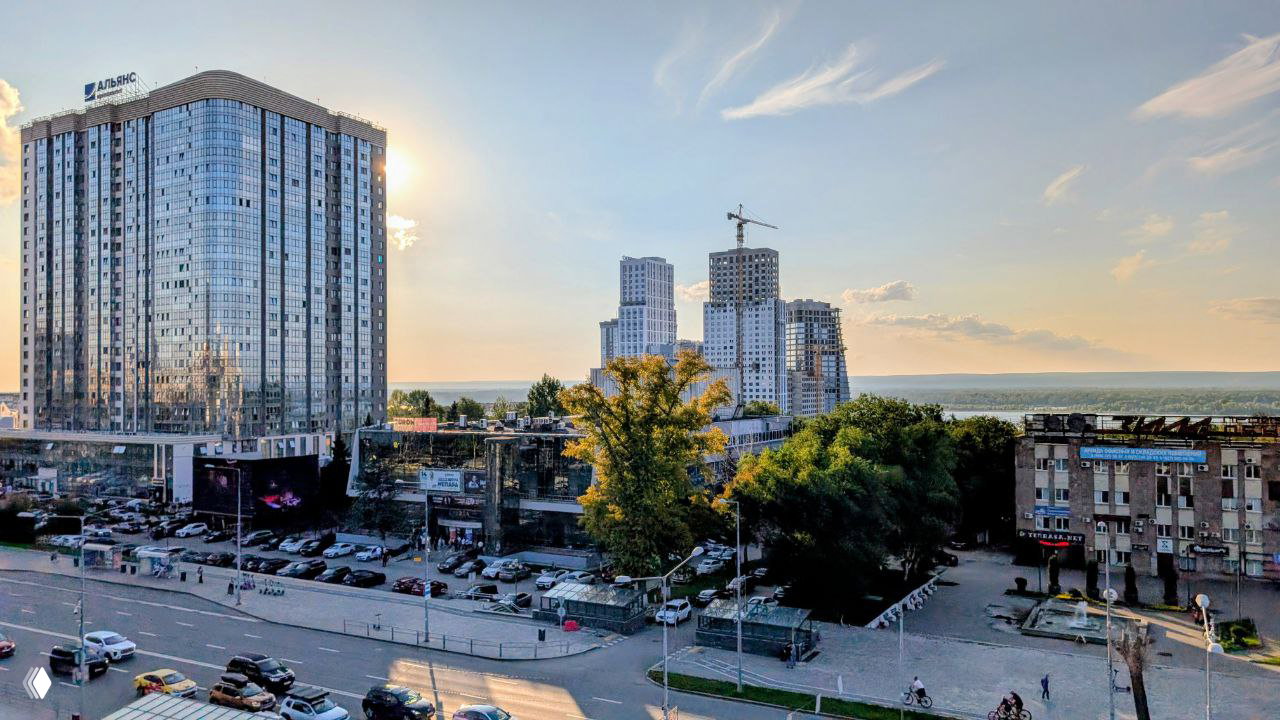 Панорамный вид с крыши: городская застройка Самары и далёкая Волга на горизонте, показывающие местный городской ландшафт.