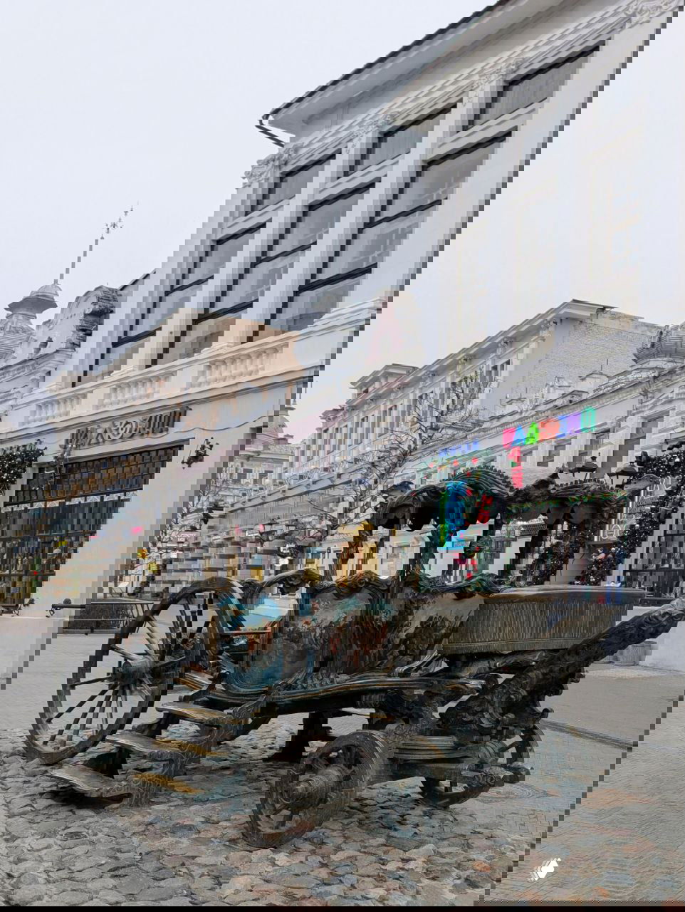 Чугунная художественно оформленная копия кареты Екатерины II, установленная на брусчатке в пешеходной зоне улицы Баумана среди исторических фасадов.