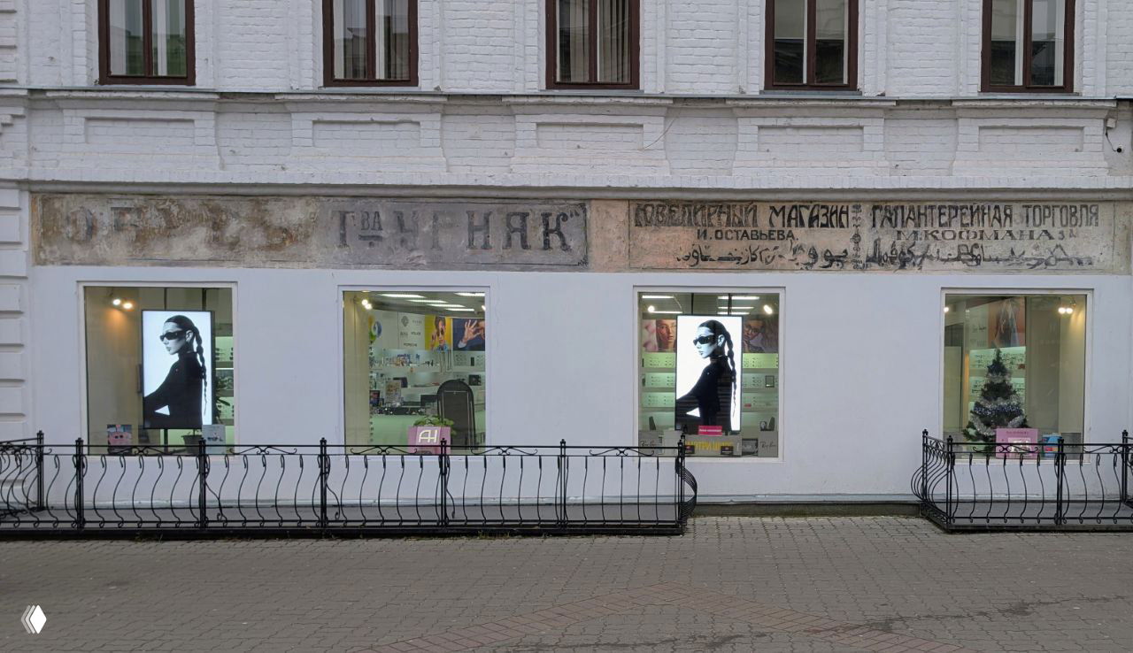 Фрагмент фасада с поздними торговыми вывесками начала XX века, обнаруженными под штукатуркой на Баумана, демонстрация реставрации и сохранения истории улицы.