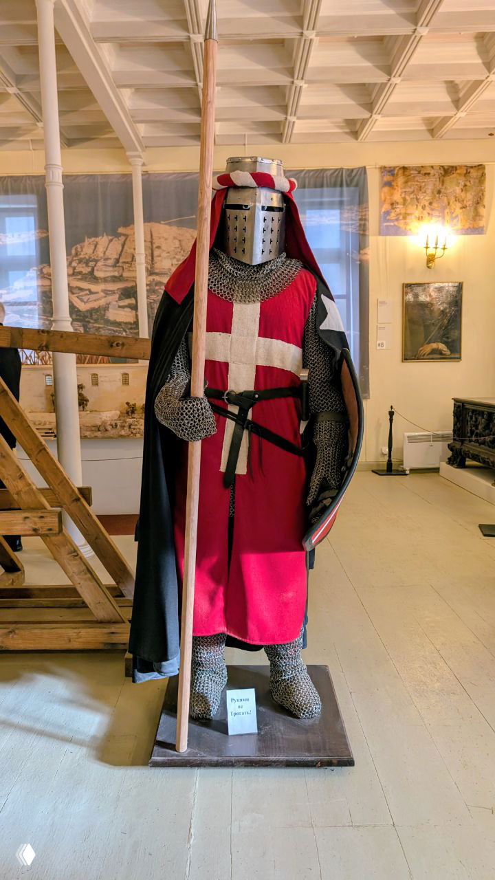 Манекен в музейной витрине в костюме крестоносца/рыцаря с кольчугой, шлемом и копьём — экспозиция, иллюстрирующая тему Мальтийского ордена.
