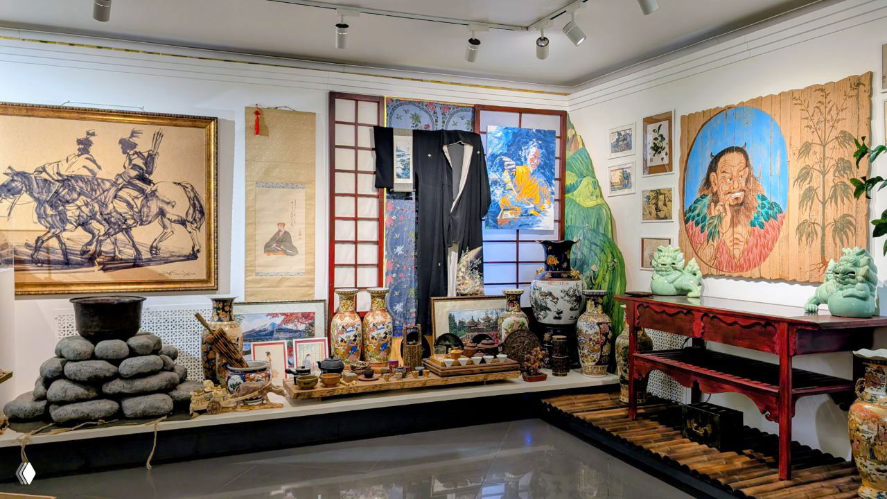 Общий вид экспозиции с разнообразными чайными предметами: вазы, статуэтки, сундуки и керамика на выставочной платформе музея