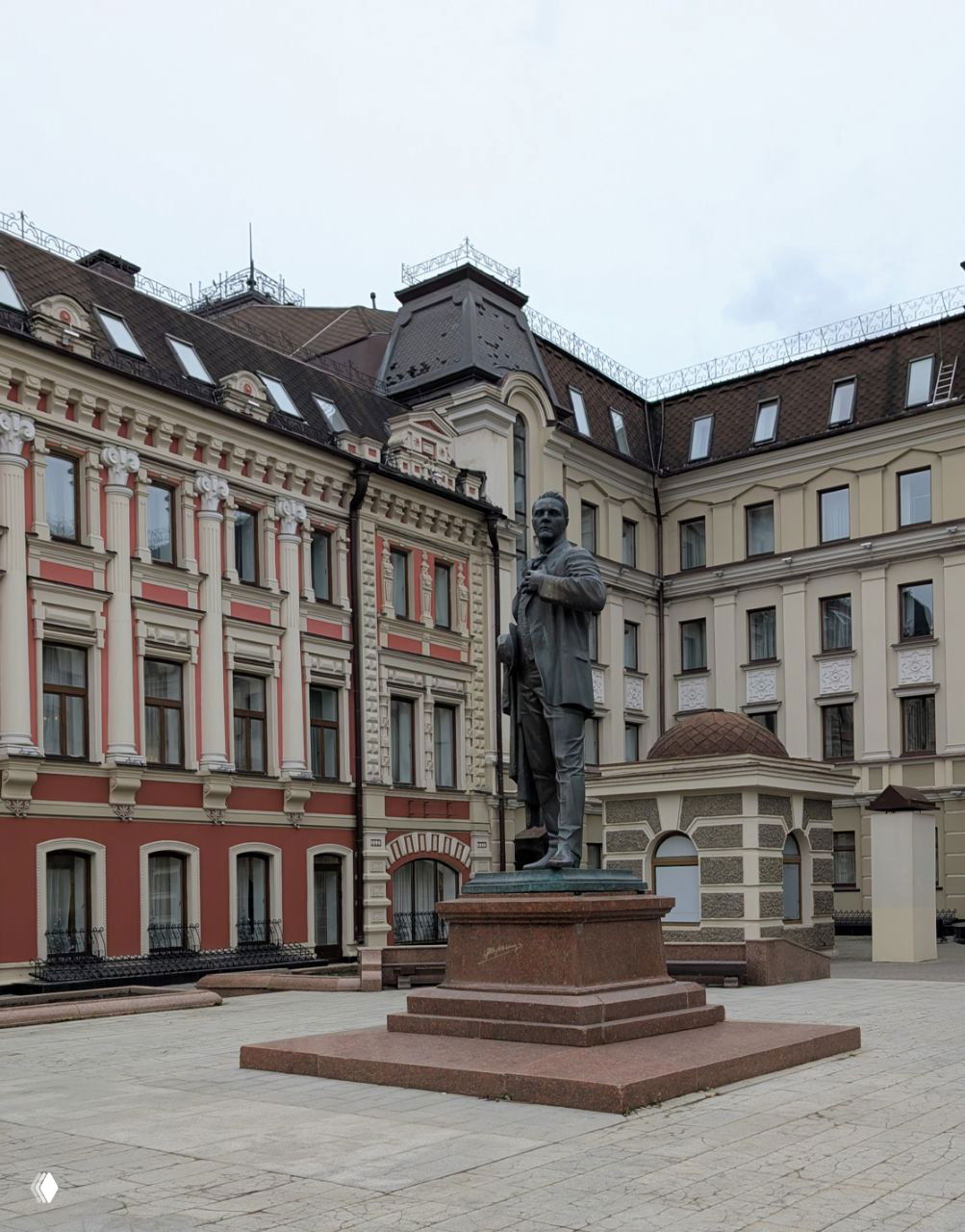 Другой ракурс площади с памятником: бронзовая скульптура артиста на постаменте на фоне исторических казанских зданий.